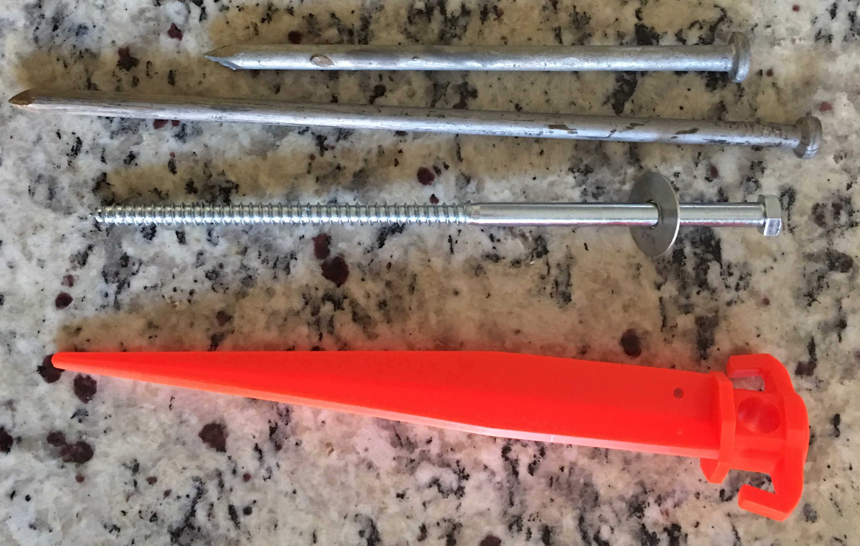 5/16- 3/8” lag screws hold much better in soft ground than plastic or metal stakes. They can also be used as expedient ground rods and fit in the base hole of pop up awnings.