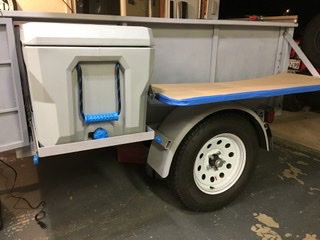 Two 5 position, swing out cantilevered side tables lock into the vertical supports and fold flat for transport. Tables will adjust from Dining table to bar counter height.  Ice chest or fridge/freezer slide out has room for one more drawer underneath.