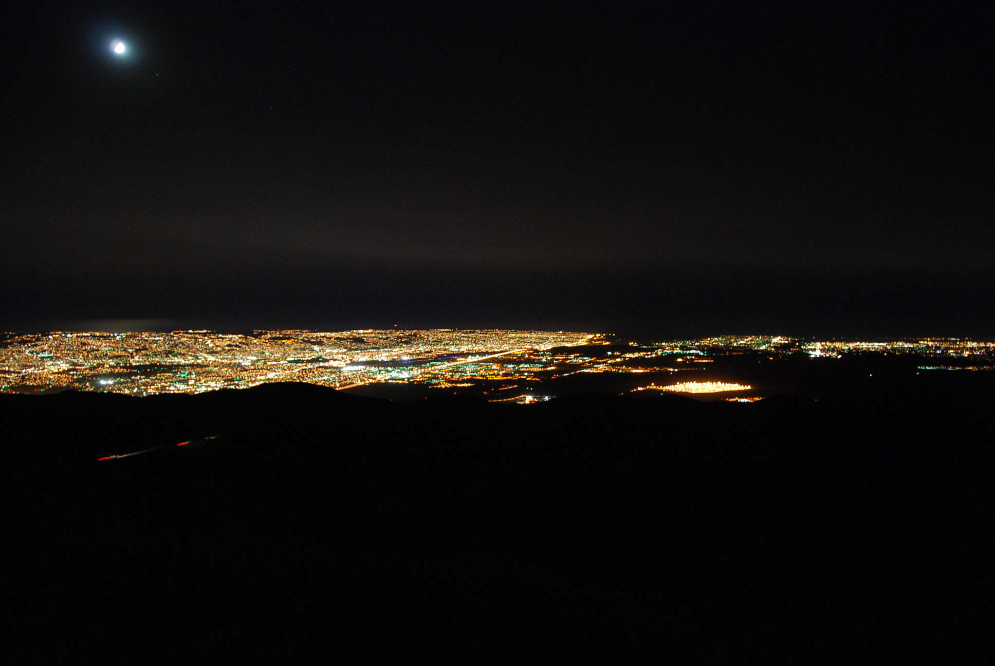 Tijuana at night. You can see the moon reflecting off of the ocean in the distance.