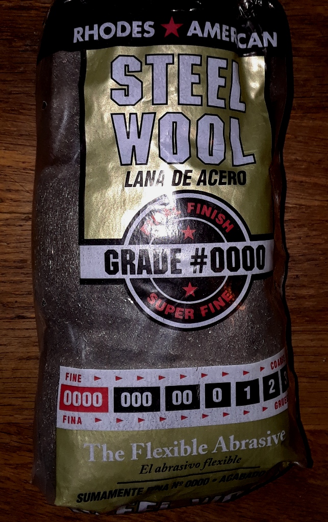 Good quality 0000 steel wool is usually safe for most finishes as is soft wire brushes made of copper, brass or bronze.  However, be very weary of coated bristles and start any cleanup in an area that will not be visible.  Slow and methodical will pay dividends when working on old finishes.