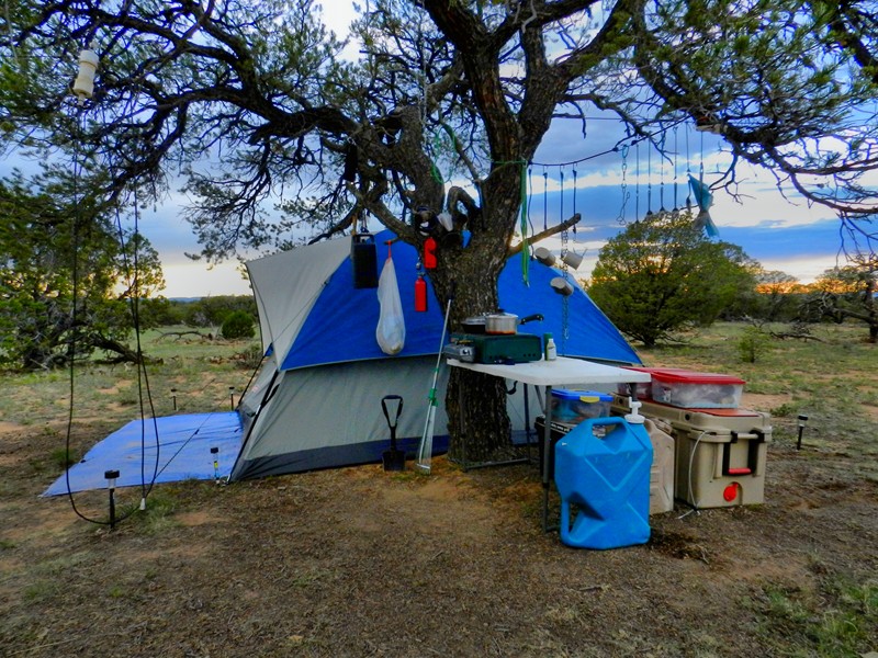 1.	Set up and ready to spend some time in the outdoors; sunset rapidly approaching.  Key items:<br />A.	Place where shade would be prevalent all day.<br />B.	In tree:  Bungees, Lantern, extra fuel canisters, utensil line.<br />C.	Above average cooler<br />D.	Plastic totes with supplies<br />E.	Lifetime table<br />F.	Coleman dual fuel stove.  Inside stove I carry source of flame/spark, wire brush, bar &amp; center level, chain &amp; wire rack for lantern, non-slip yoga mat piece for under stove that also acts to keep things from banging around during travel.<br />G.	Coleman dual fuel lantern in case.  In the bottom of the case I keep matches and extra mantles<br />H.	GI Canteen cups