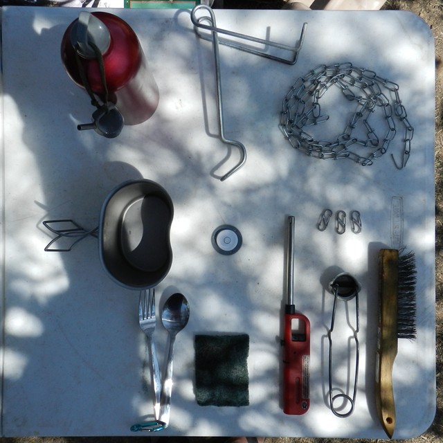 01:  Lifetime folding table, chain for hanging Coleman lantern, USGI canteen cup, striker, steel brush/green pad, carbiners, fuel spot and post level.